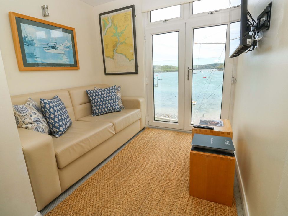 A living room with a couch and a window overlooking the water at 24 The Salcombe in Salcombe