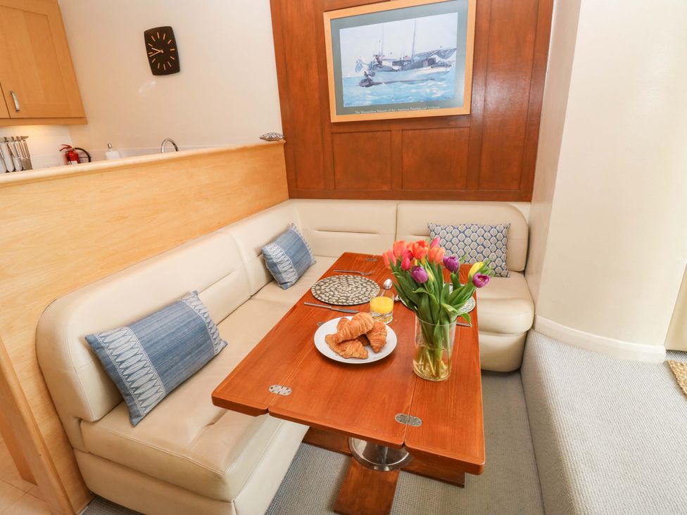 A dining room with a table and sofa at 24 The Salcombe in Salcombe