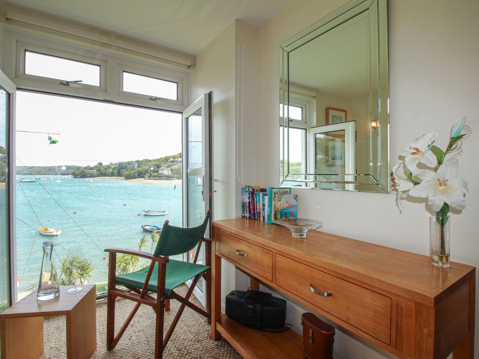 A room with a table and chair and a view of the water at 24 The Salcombe in Salcombe