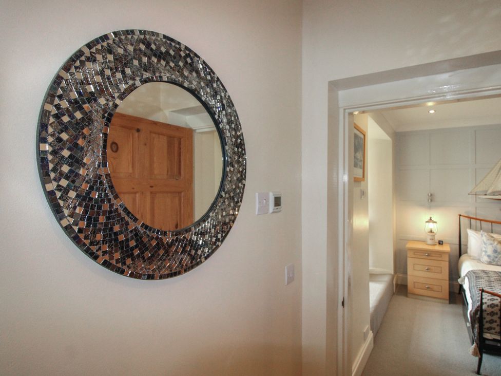 A bedroom with a mirror and furniture at 24 The Salcombe in Salcombe