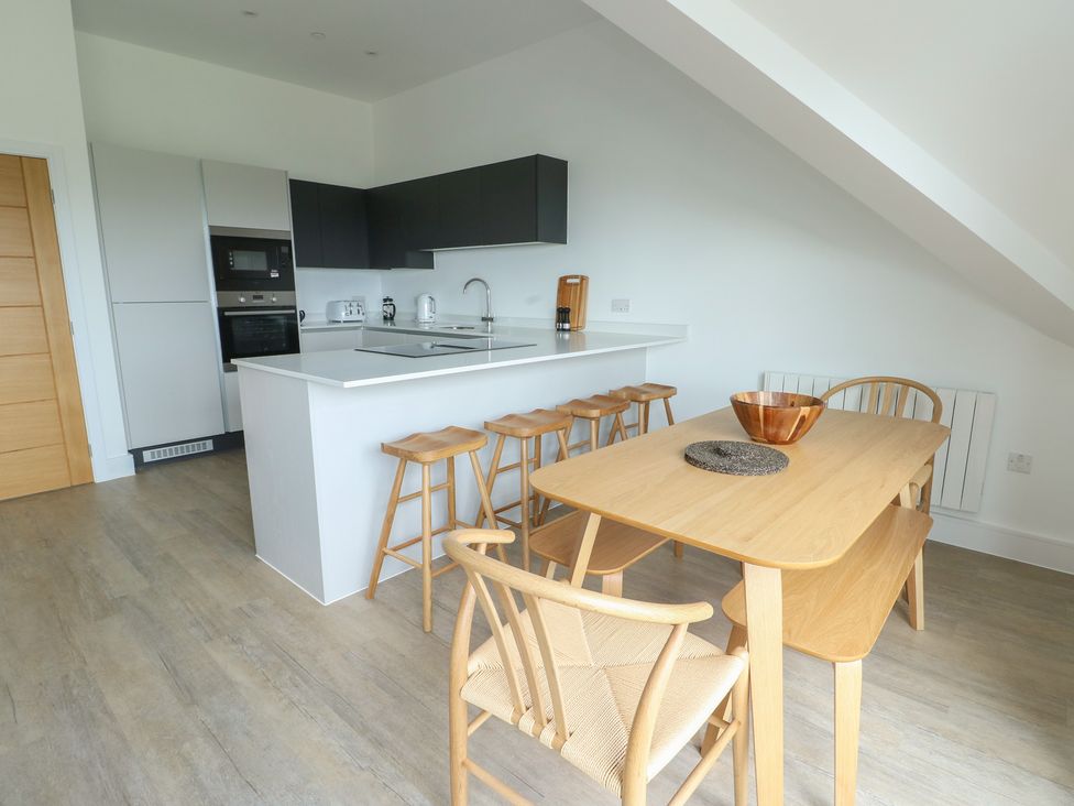 A kitchen with bar stools and dining table at Glynllifon 8 Marian-glas near Benllech