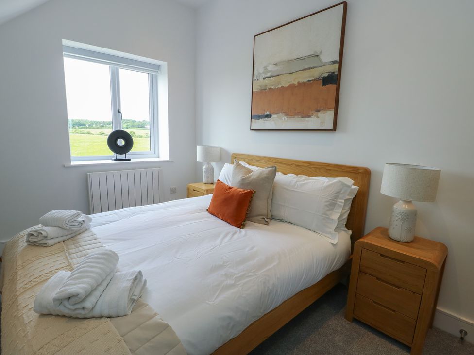 A bedroom with a double bed and bedside table at Glynllifon 8 Marian-glas near Benllech