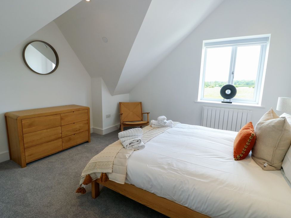 A bedroom with a bed and dresser at Glynllifon 8 Marian-glas near Benllech