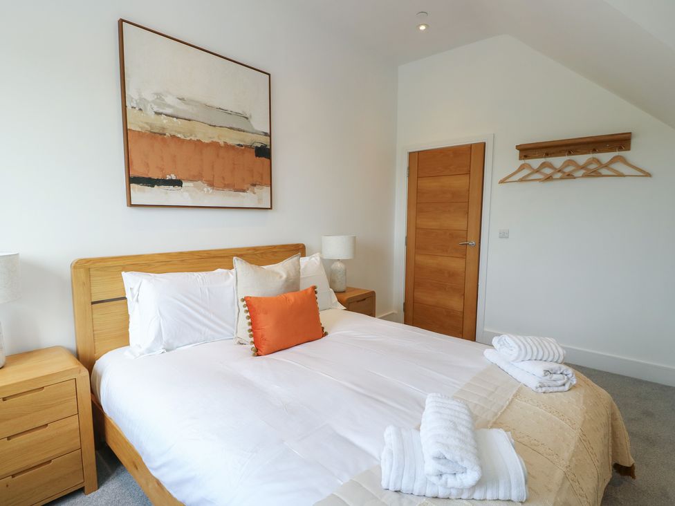 A bedroom with a bed, nightstands, and artwork at Glynllifon 8 Marian-glas near Benllech