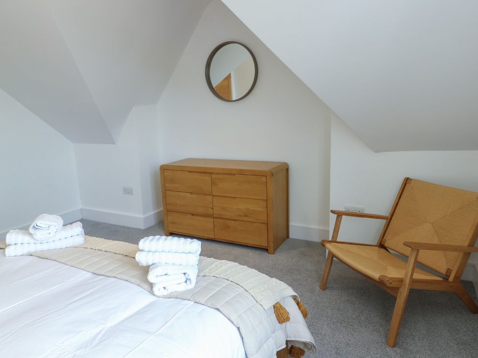 A bedroom with a bed, towels, dresser and chair at Glynllifon 8 Marian-glas near Benllech