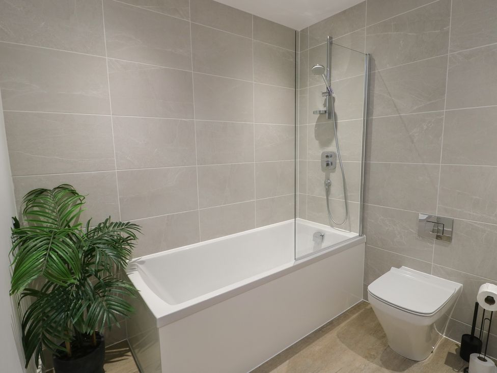 A bathroom with a bathtub and a toilet at Glynllifon 8 Marian-glas near Benllech