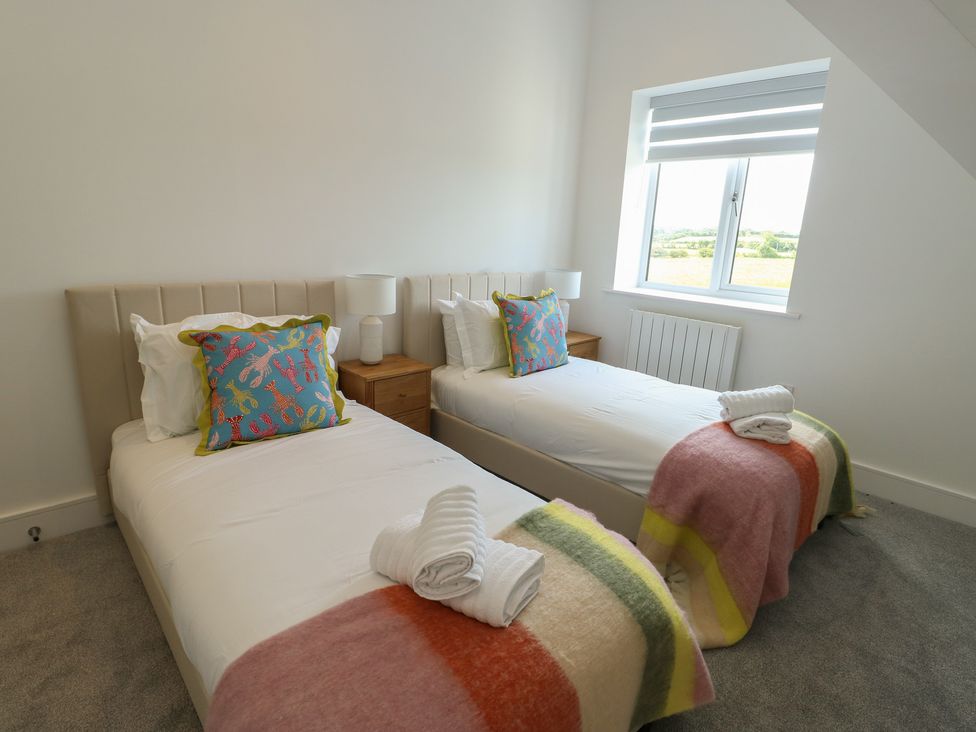 A bedroom with two single beds and a window at Glynllifon 8 in Marian-glas near Benllech