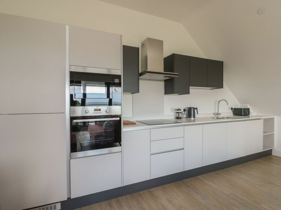 A kitchen with modern appliances and cabinetry at Glynllifon 8 Marian-glas near Benllech