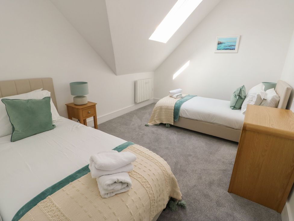 A bedroom with two beds and a bedside table at Glynllifon 8 in Marian-glas near Benllech
