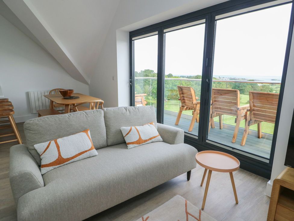 A living room with a sofa and dining area at Glynllifon 9 Marian-glas near Benllech