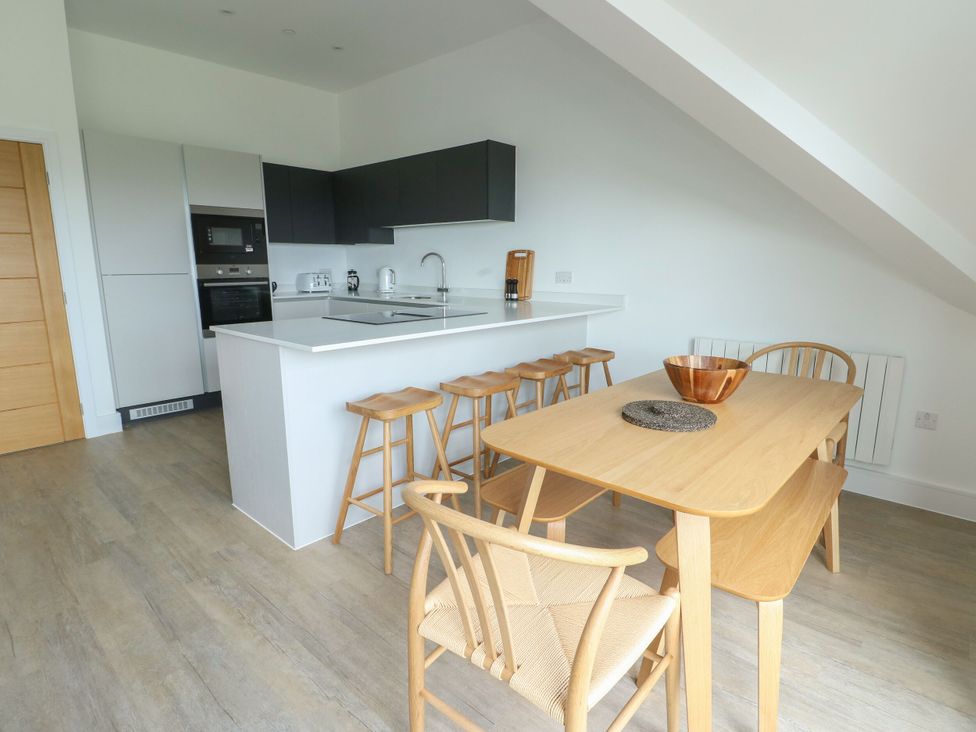 A kitchen with a dining table and stools at Glynllifon 9 Marian-glas near Benllech