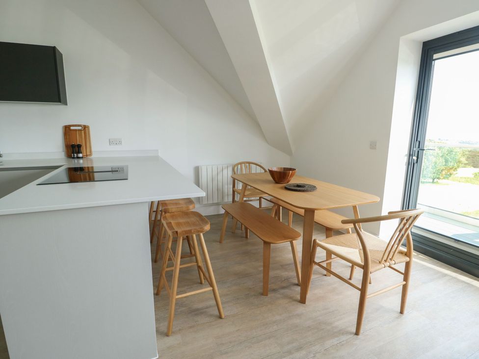 A kitchen with a dining area featuring a table and chairs at Glynllifon 9 in Marian-glas near Benllech