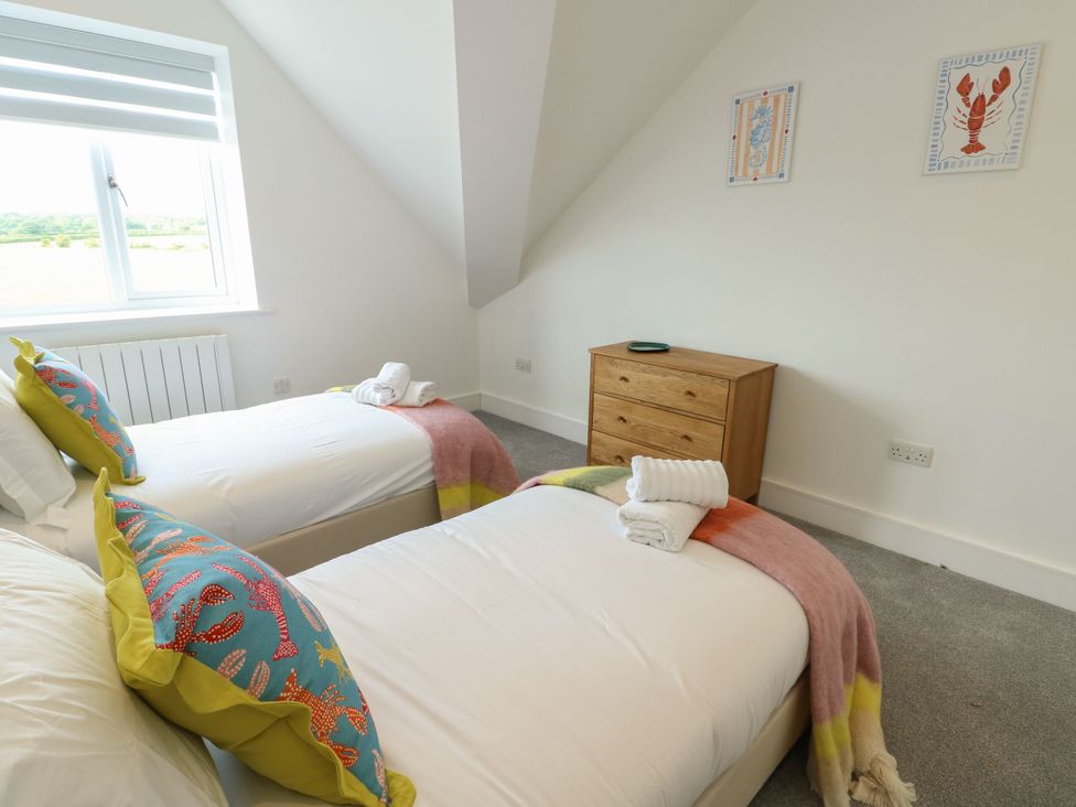 A bedroom with two beds and a wooden drawer at Glynllifon 9 Marian-glas near Benllech