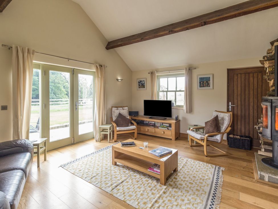 A living room with a sofa, table, and television at Orchard Cottage in Durham