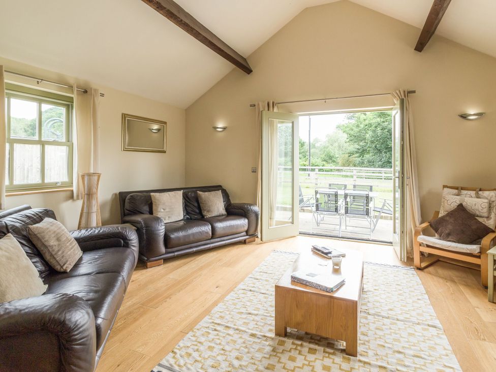 A living room with sofas and a door leading outside at Orchard Cottage in Durham
