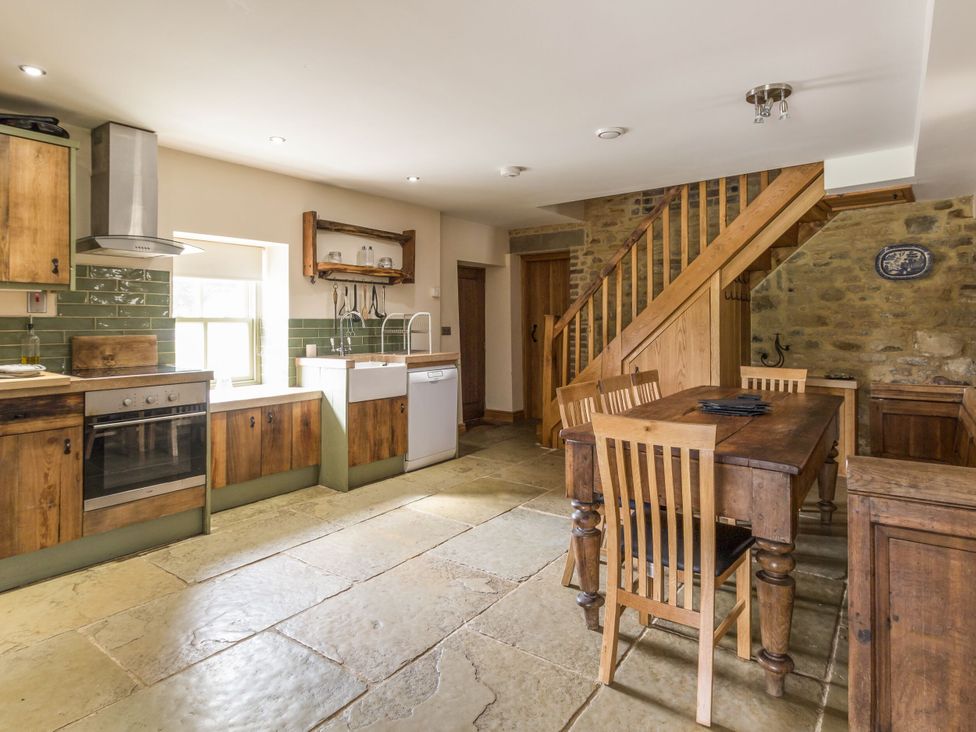 A kitchen with cabinets, sink, and dining table at Orchard Cottage in Durham