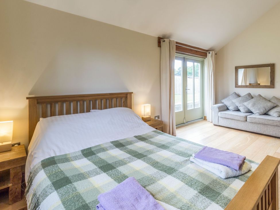 A bedroom with a bed and couch at Orchard Cottage in Durham