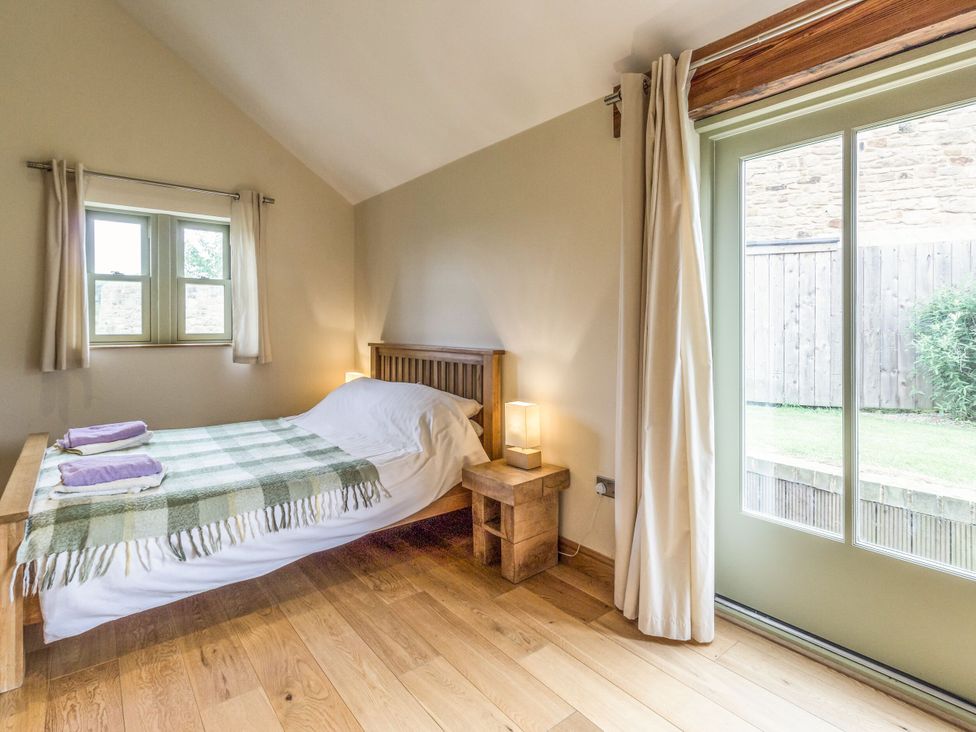 A bedroom with a bed and windows at Orchard Cottage in Durham