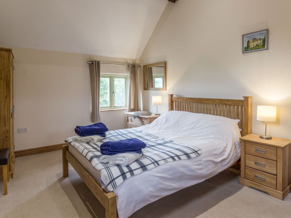 A bedroom with a bed and nightstand at Orchard Cottage in Durham