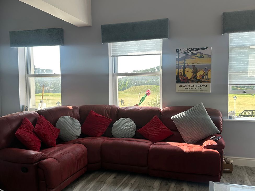 A living room with a red sofa and cushions at Sugar loft in Silloth