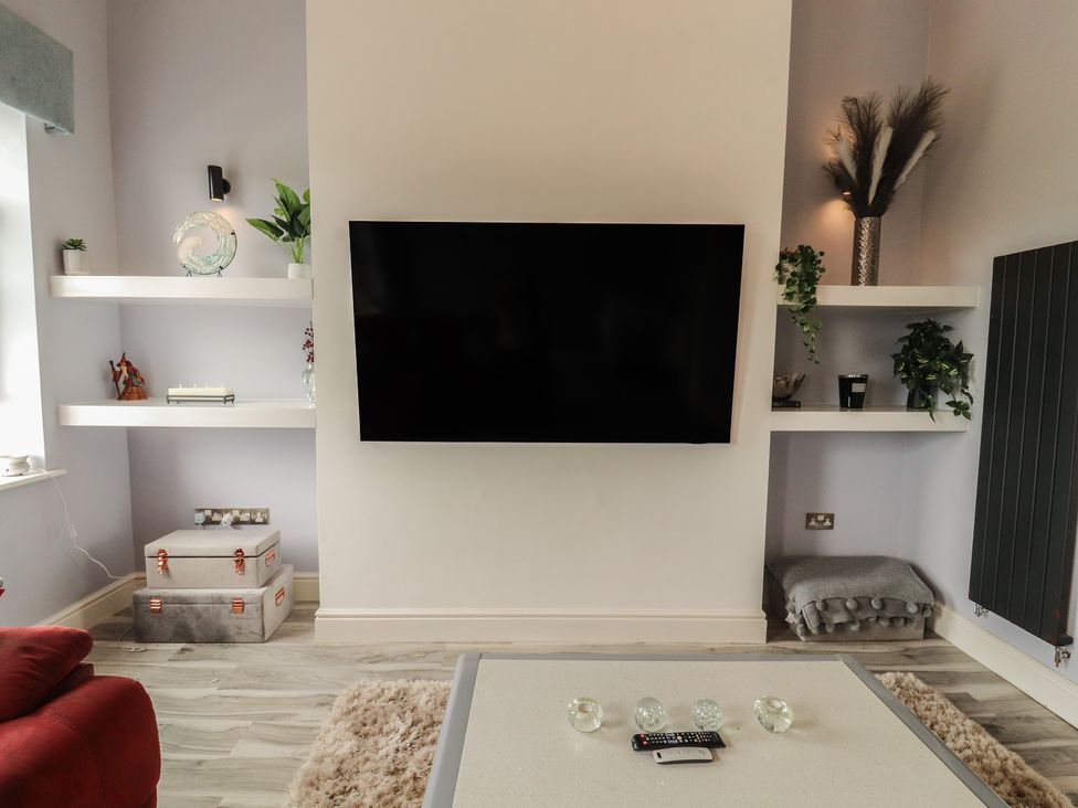 A living room with a TV and shelves at Sugar Loft Silloth