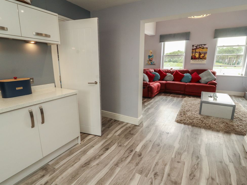 A kitchen area leading to a living room with a red sofa at Sugar Loft in Silloth
