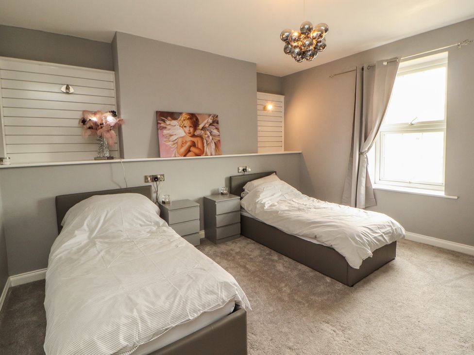 A bedroom with two beds and a painting at Sugar Loft in Silloth