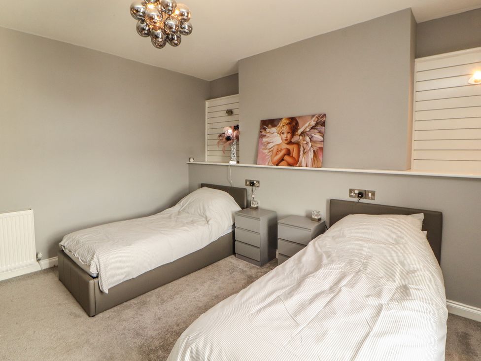 A bedroom with two beds and a painting at Sugar Loft in Silloth