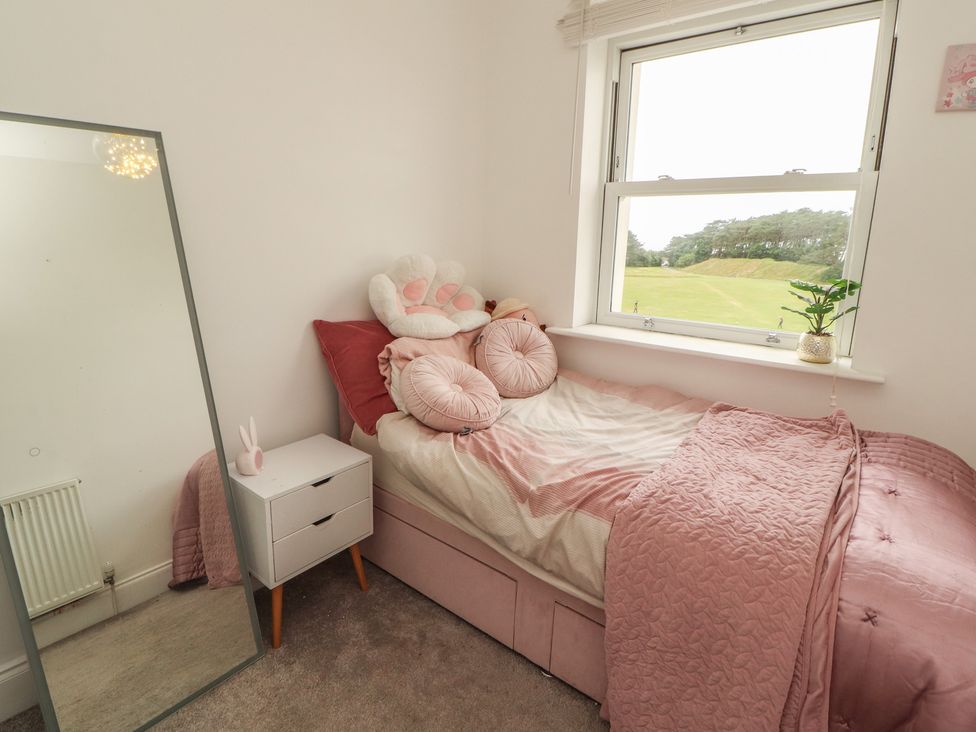 A bedroom with a bed, mirror, and side table at Sugar Loft in Silloth