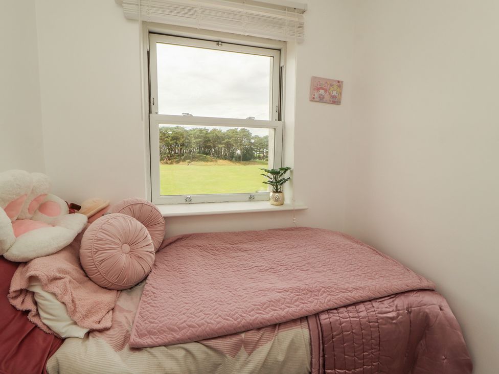 A bedroom with a bed and a window overlooking a field at Sugar Loft in Silloth