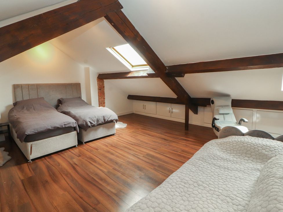 A bedroom with two beds and a chair at Sugar Loft in Silloth