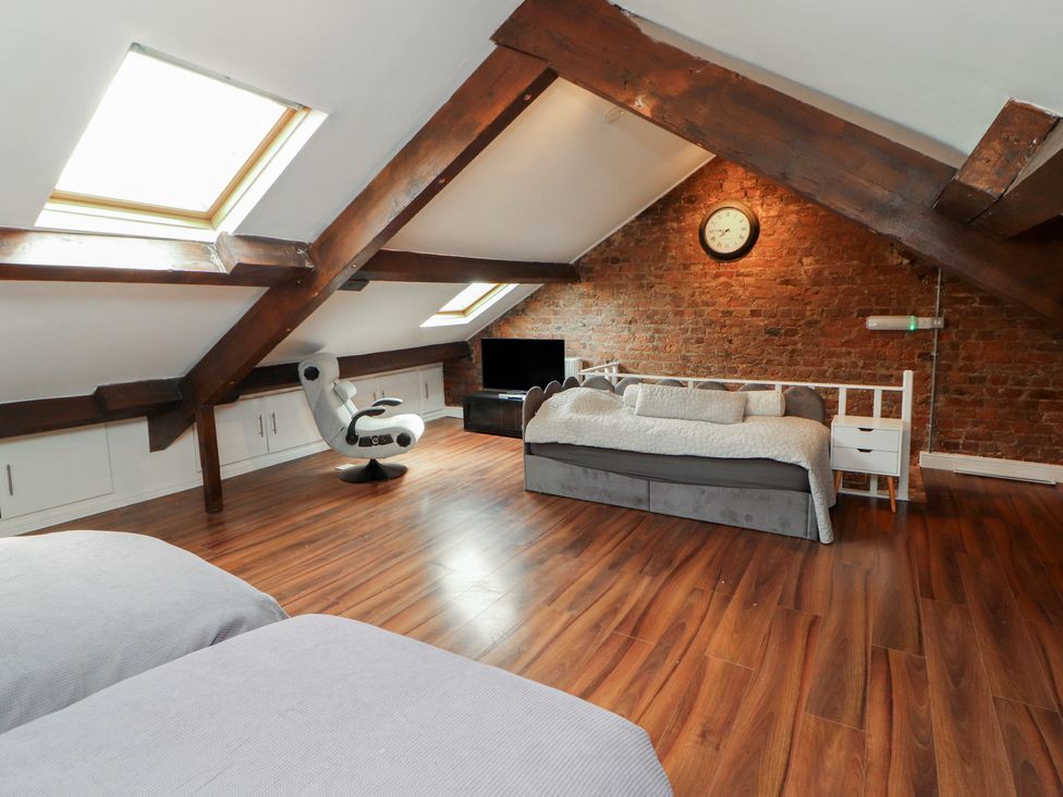 An attic with a bed and sofa at Sugar Loft in Silloth