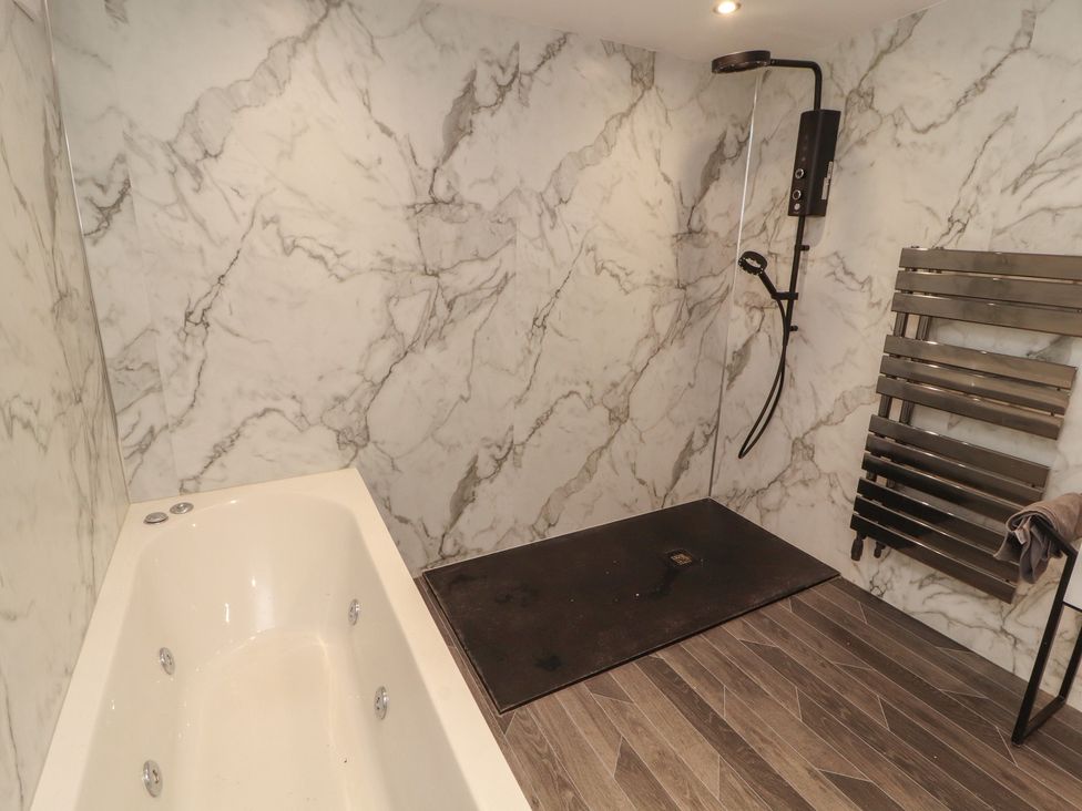 A bathroom with a bathtub and shower at Sugar Loft in Silloth