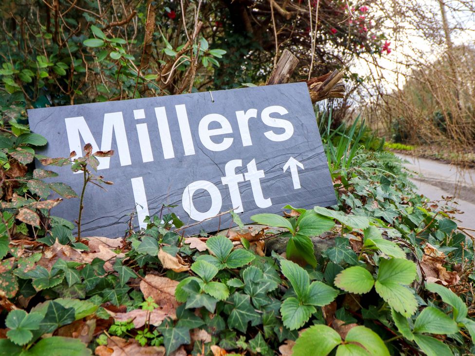 A sign for Millers Loft surrounded by plants in Llanrwst