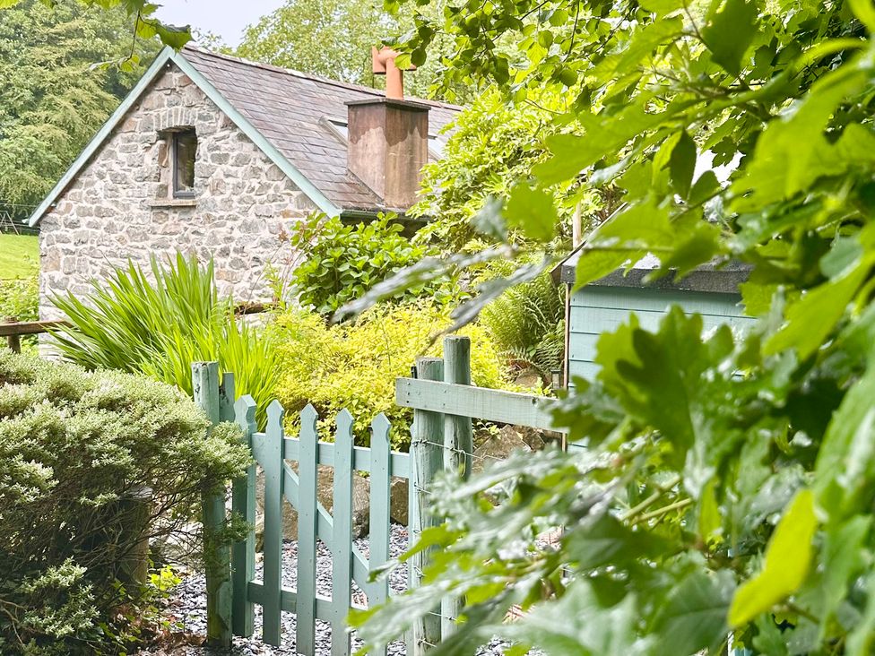 A stone cottage with a garden and wooden fence at Millers Loft in Maenan near Llanrwst