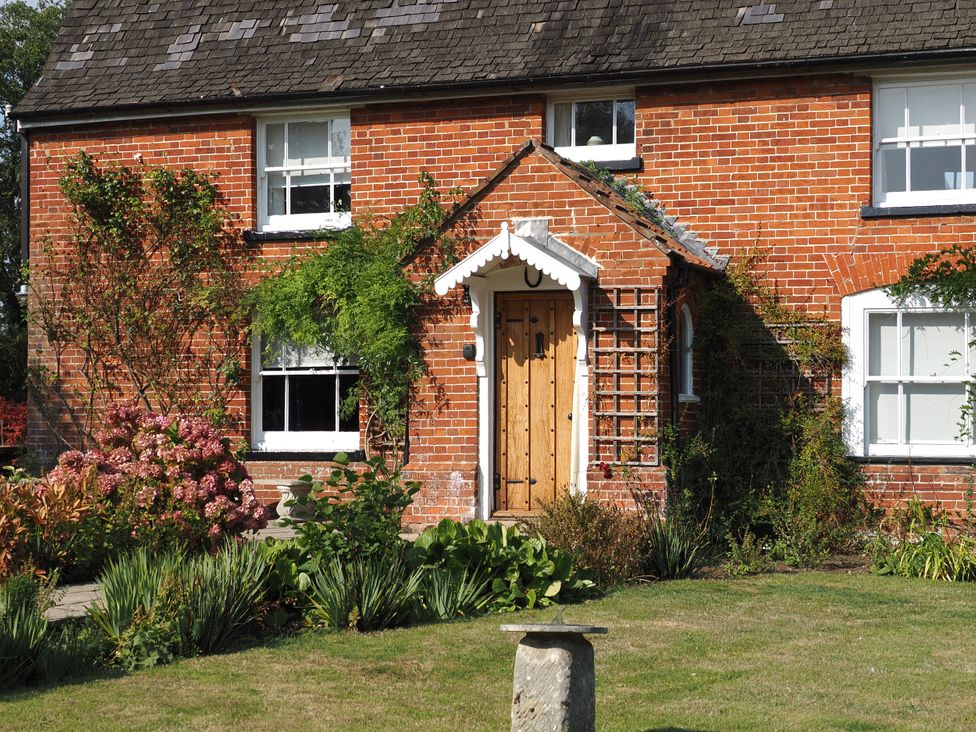 A brick house with a flower bed at Cutbush Farmhouse in Norwich