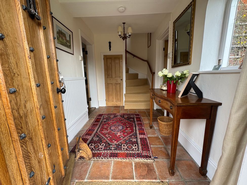 A hallway with a table and flowers at Cutbush Farmhouse in Norwich