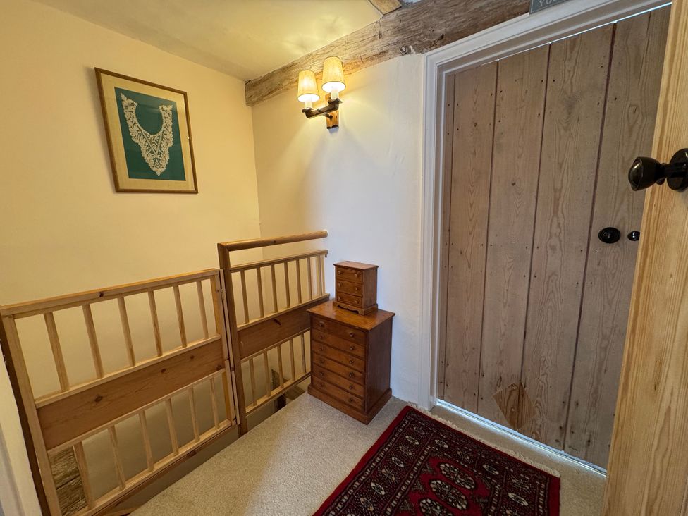 A hallway with a wooden door and chest of drawers at Cutbush Farmhouse in Norwich