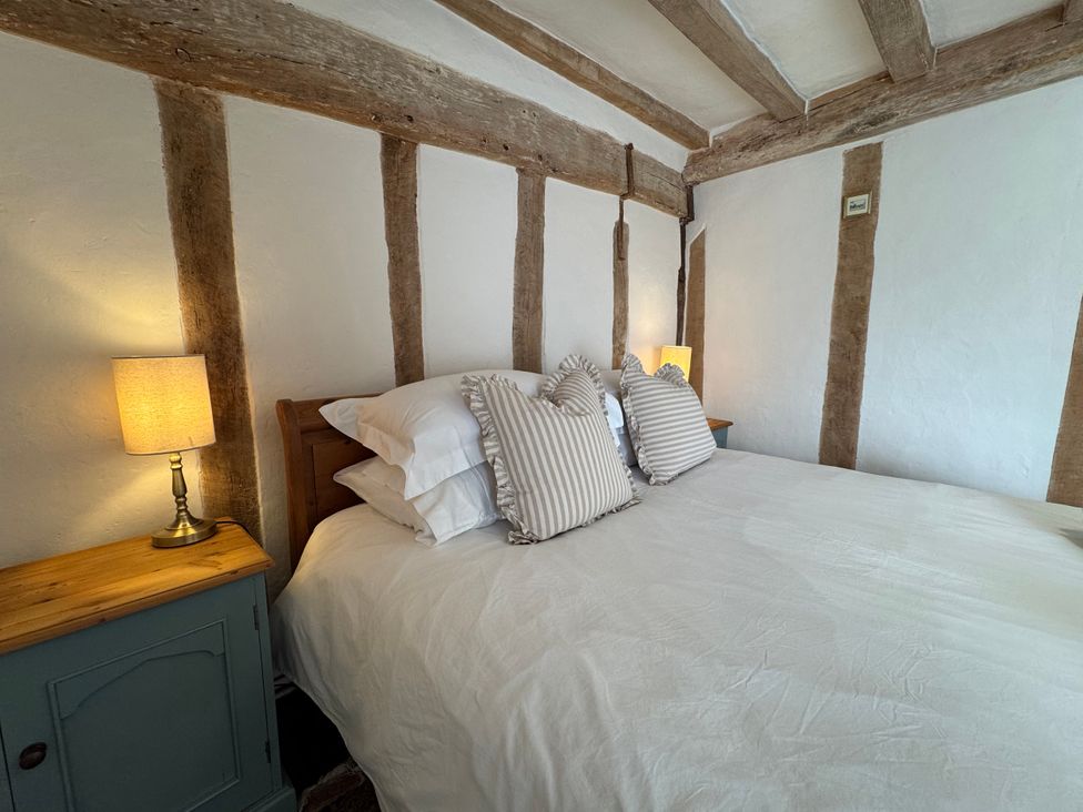 A bedroom with a bed and side table at Cutbush Farmhouse in Norwich