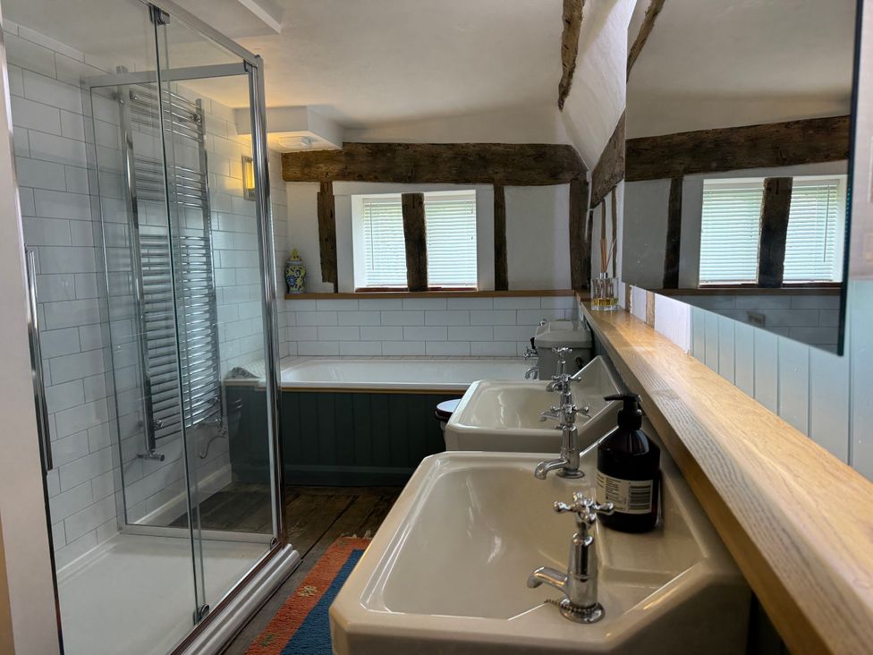 A bathroom with a shower, bathtub, and two sinks at Cutbush Farmhouse in Norwich