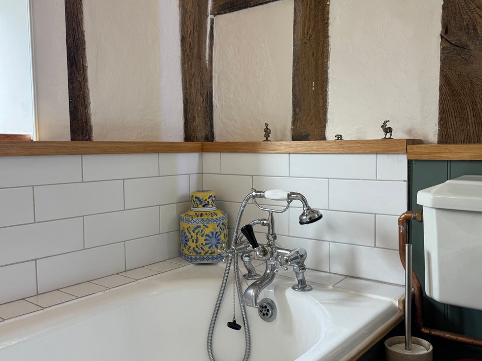 A bathroom with a bathtub and sink faucet at Cutbush Farmhouse Norwich