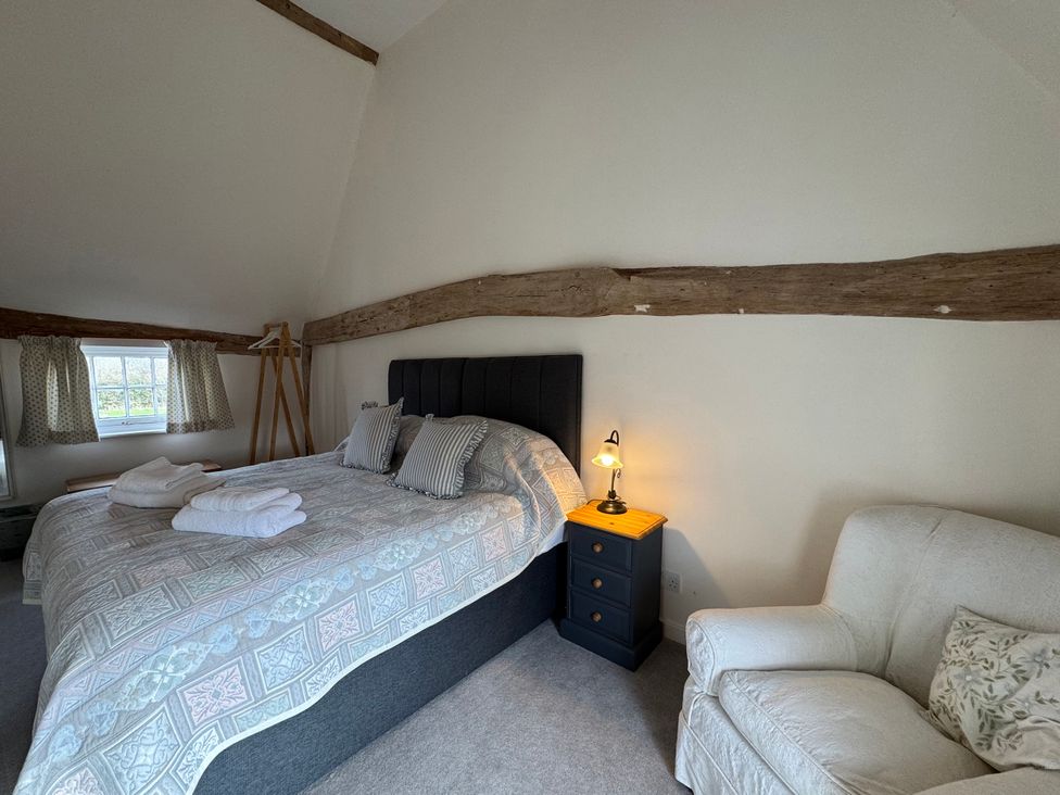 A bedroom with a bed and nightstand at Cutbush Farmhouse in Norwich