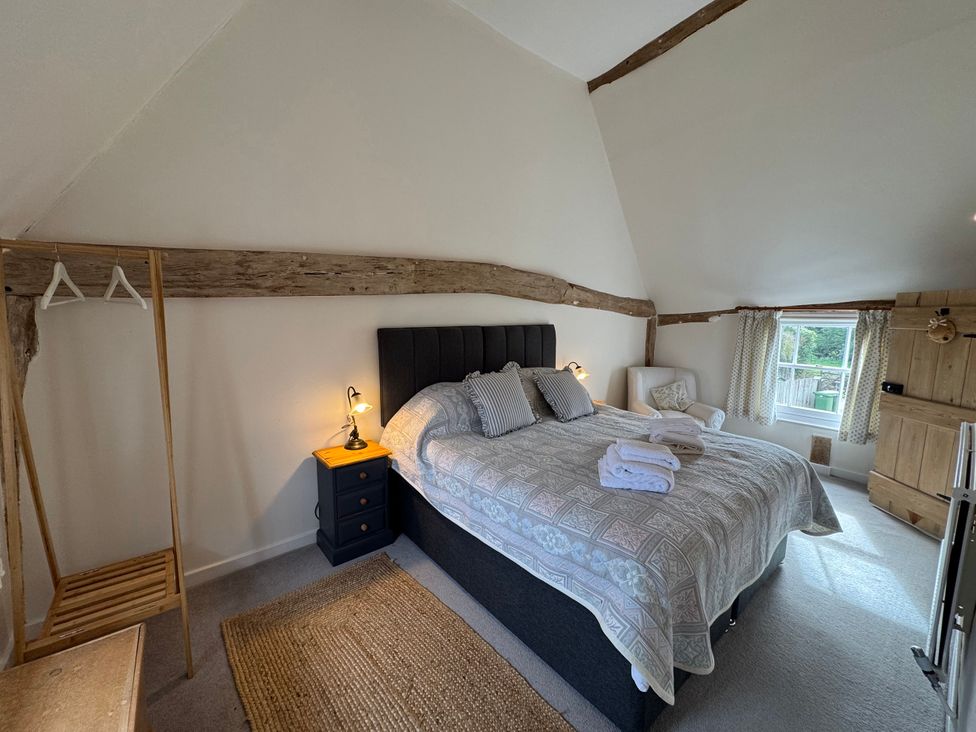 A bedroom with a bed and nightstand at Cutbush Farmhouse in Norwich