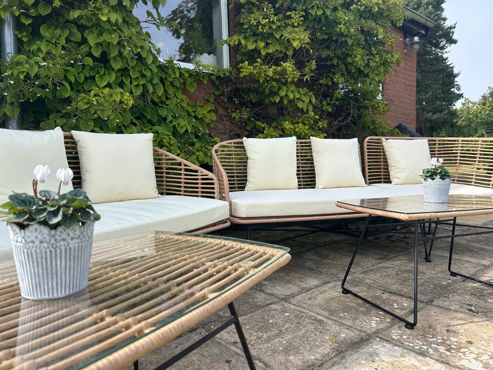 An outdoor seating area with a sofa and table at Cutbush Farmhouse in Norwich