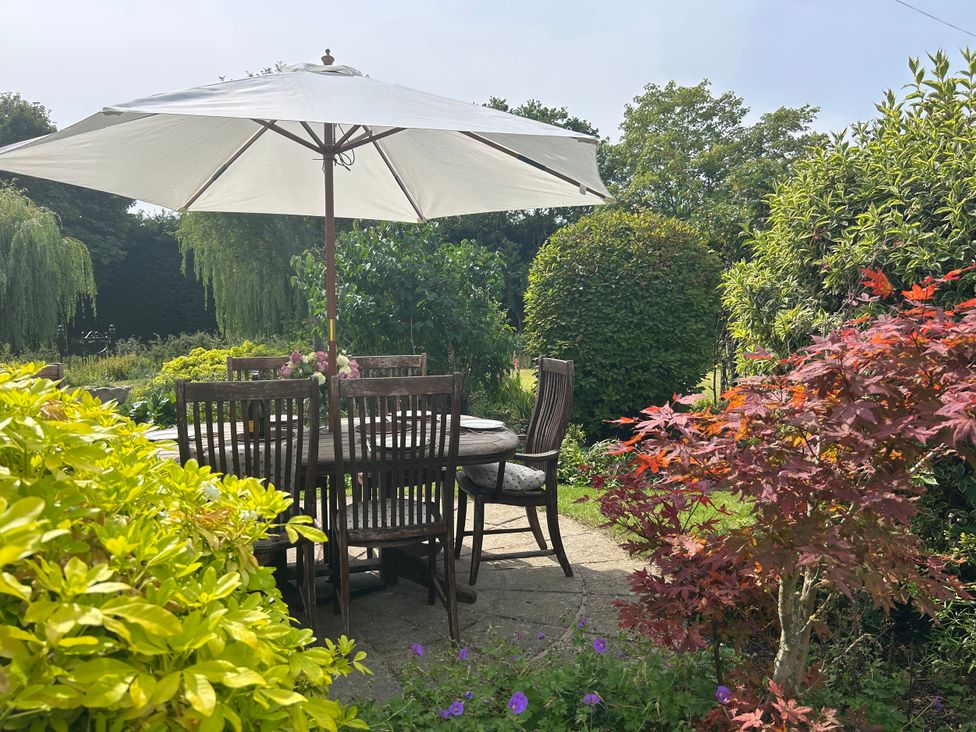 A garden with a table and chairs under an umbrella at Cutbush Farmhouse in Norwich