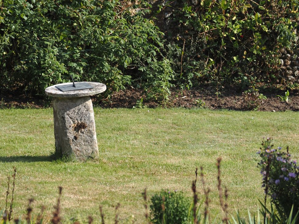 A sundial on a stone base in a garden at Cutbush Farmhouse in Norwich