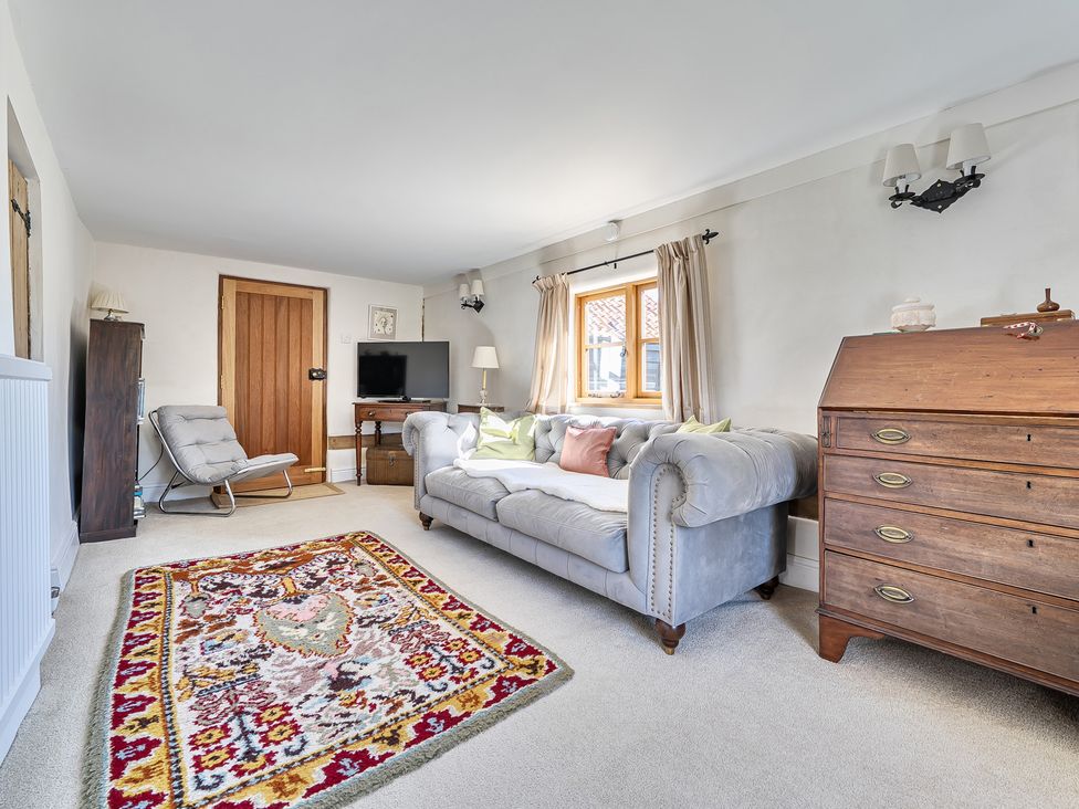 A living room with a sofa and a rug at Cutbush Farmhouse in Hingham