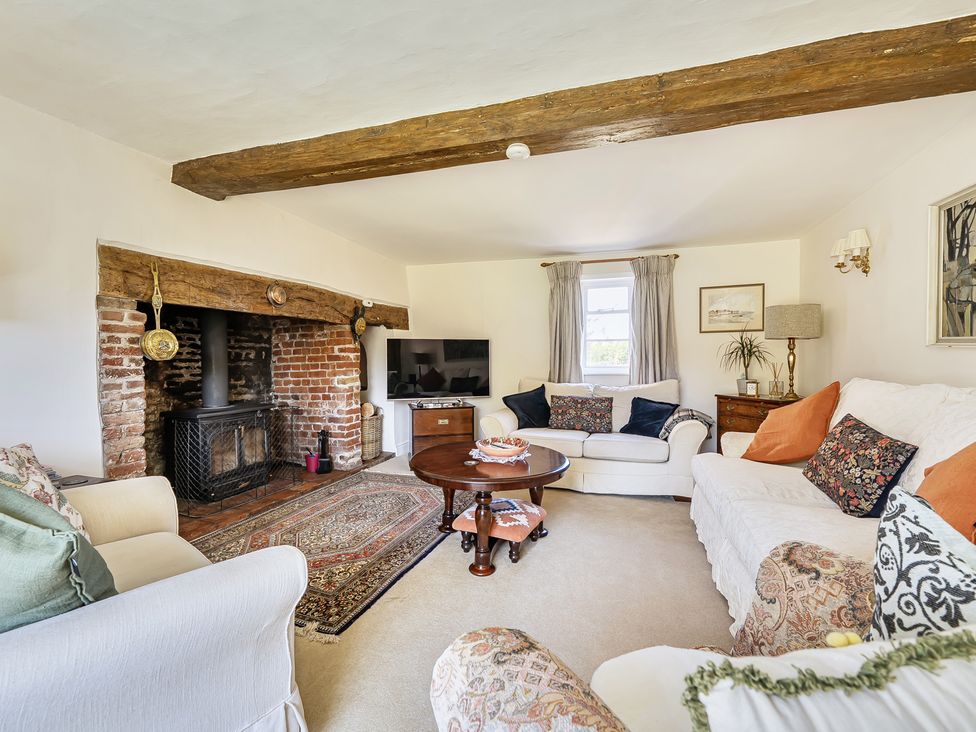 A living room with a fireplace and sofas at Cutbush Farmhouse in Hingham