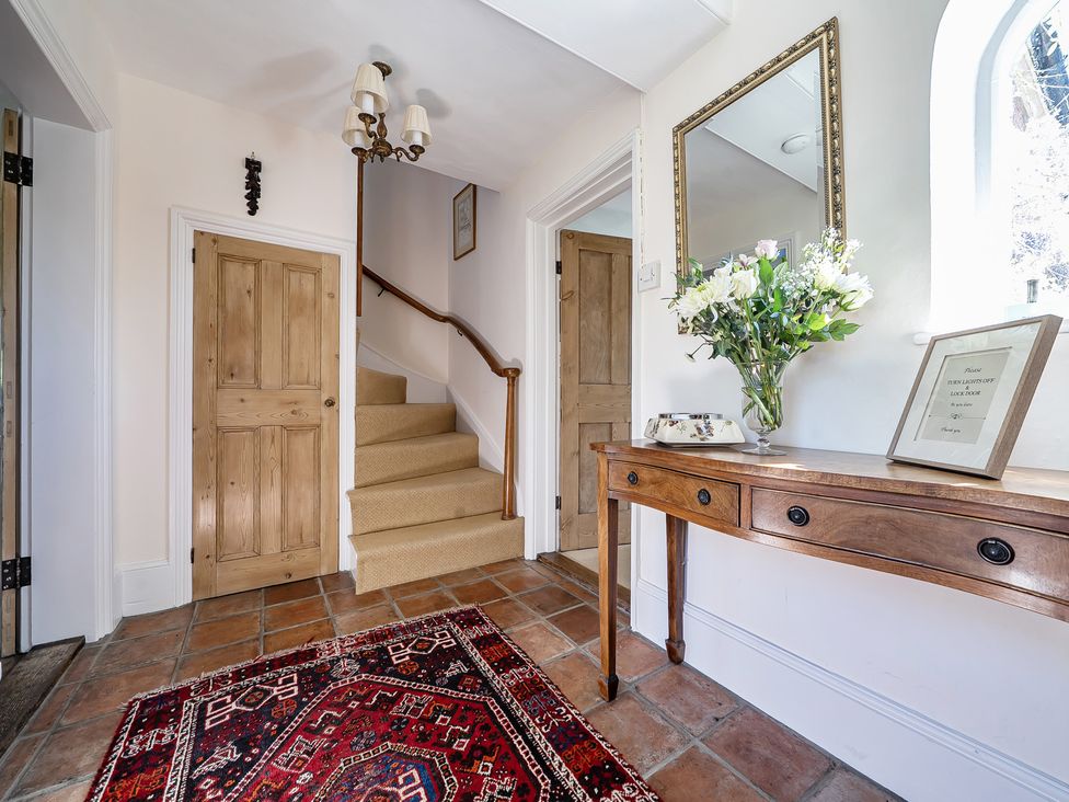 A hallway with a staircase and a table at Cutbush Farmhouse in Hingham