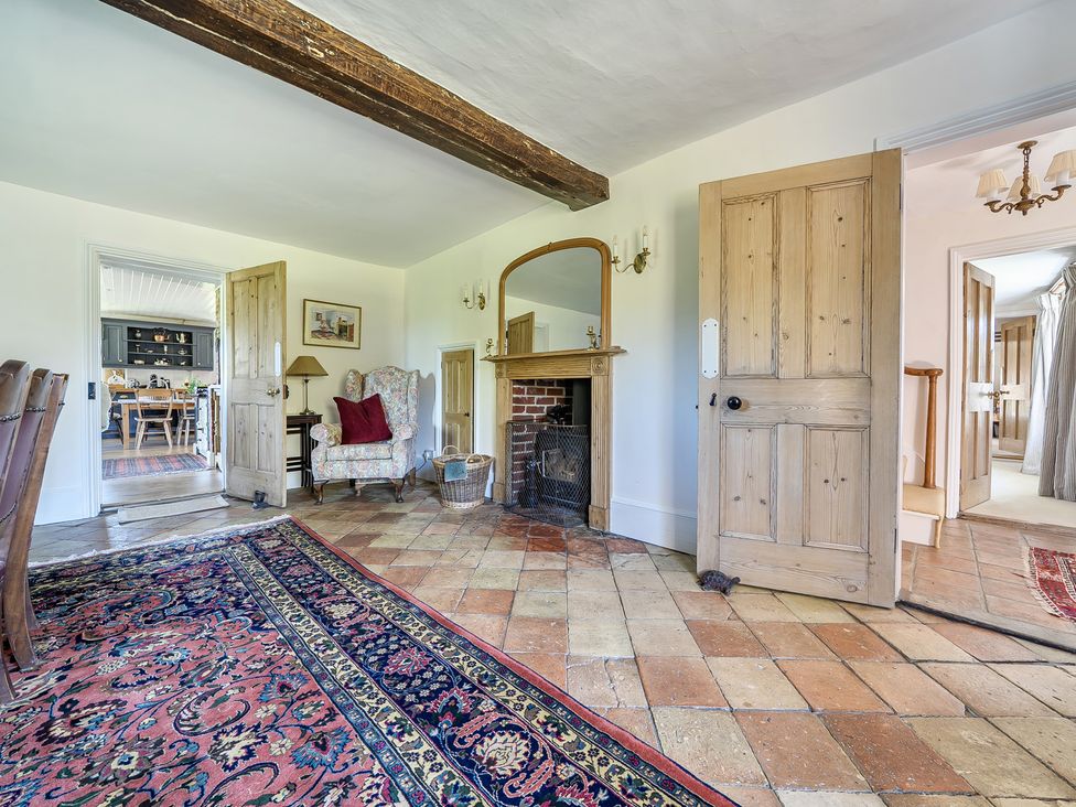 A living room with a fireplace and armchair at Cutbush Farmhouse Hingham